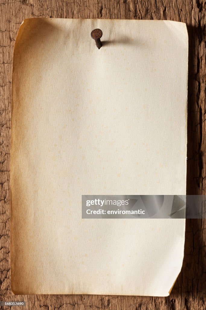 Old paper nailed to a weathered wooden board.