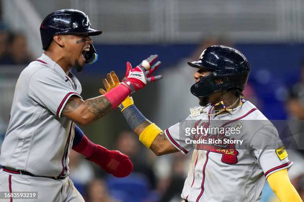 Orlando Arcia of the Atlanta Braves celebrates with Ronald Acuna Jr. #13 after both scoring against the Miami Marlins during the sixth inning at...