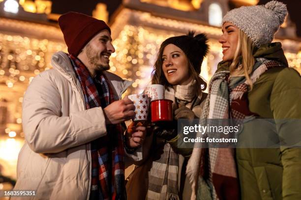 small group of friends standing on the city street and enjoying mulled wine - mulled wine stock pictures, royalty-free photos & images