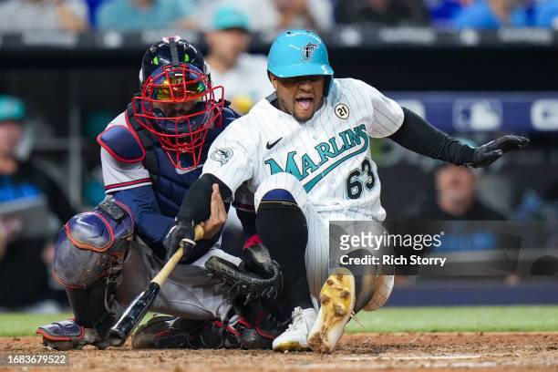 Travis d'Arnaud of the Atlanta Braves holds up Xavier Edwards of the Miami Marlins after he was hit by a pitch during the seventh inning at loanDepot...