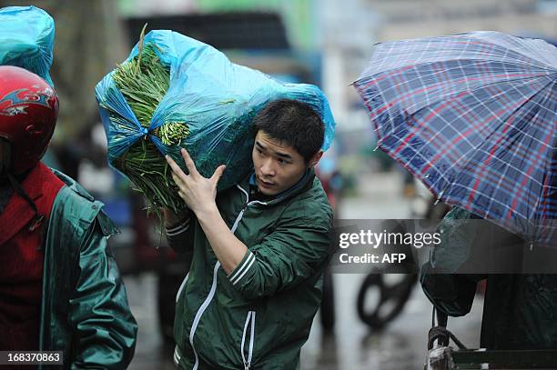 Man carries a bag of vegetables in the rain in Hefei, east China's Anhui province on May 9, 2013. Inflation in China accelerated to 2.4 percent...