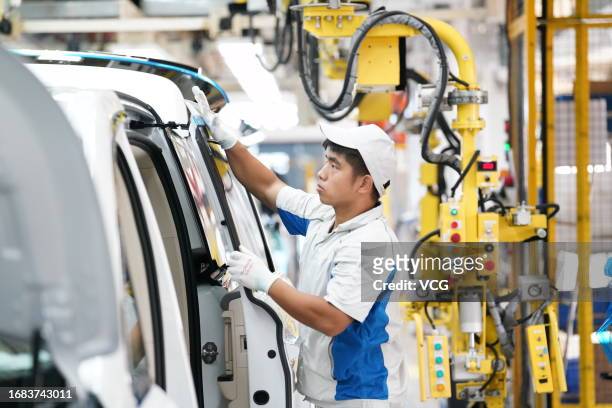An employee works on the assembly line of Voyah electric vehicles at Dongfeng Motor's Voyah Automobile factory on August 23, 2023 in Wuhan, Hubei...