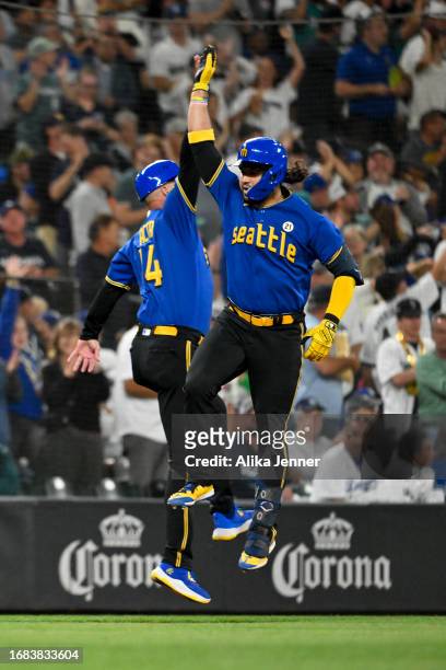 Eugenio Suarez of the Seattle Mariners celebrates with third base coach Manny Acta after hitting a solo home run during the fourth inning against the...