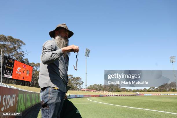 Snake catcher picks up a snake on the sideline during the round three AFLW match between Greater Western Sydney Giants and Richmond Tigers at...