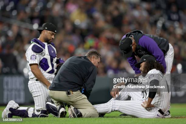 Pitcher Justin Lawrence of the Colorado Rockies is attended to by Elias Diaz, trainer Keith Duggar and Manager Bud Black after injuring his ankle...