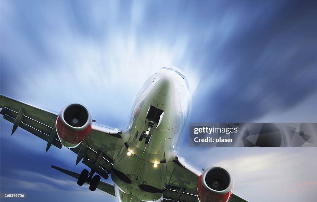 Sunlit airplane taking off against dramatic sky