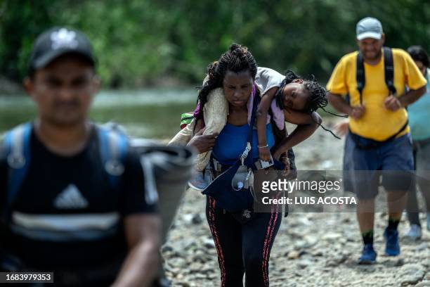 Migrant woman walks by the jungle carrying her daughter near Bajo Chiquito village, the first border control of the Darien Province in Panama, on...