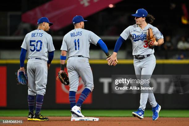 Mookie Betts of the Los Angeles Dodgers, Miguel Rojas, and James Outman celebrate after the game against the Seattle Mariners at T-Mobile Park on...