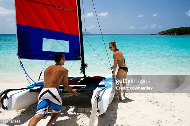 pareja impulsar catamarán en agua para navegar - catamarán fotografías e imágenes de stock