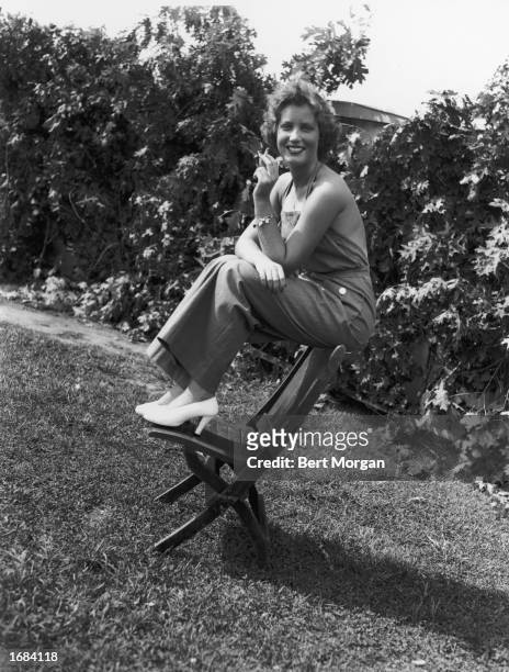 American socialite Edith Beale smokes a cigarette while sitting outdoors in overalls at the East Hampton Fair, East Hampton, Long Island, New York,...