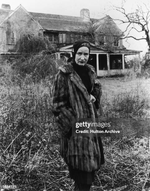 American socialite Edith Beale Jr. Wears a fur coat while posing in front of her dilapidated East Hampton, Long Island, mansion in a still from the...