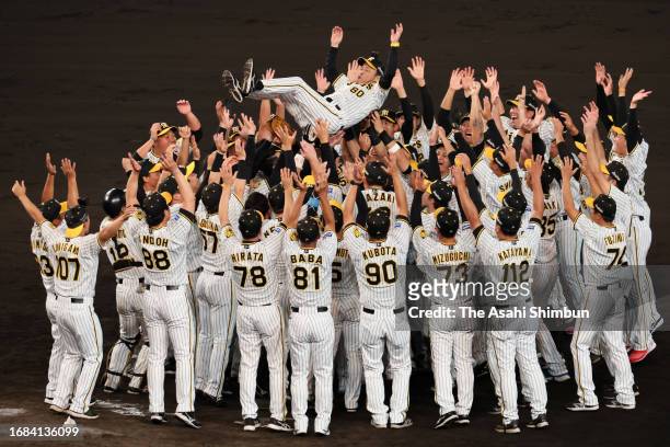 Head coach Akinobu Okada of the Hanshin Tigers is tossed into the air as the team celebrates the Central League season champions following the game...