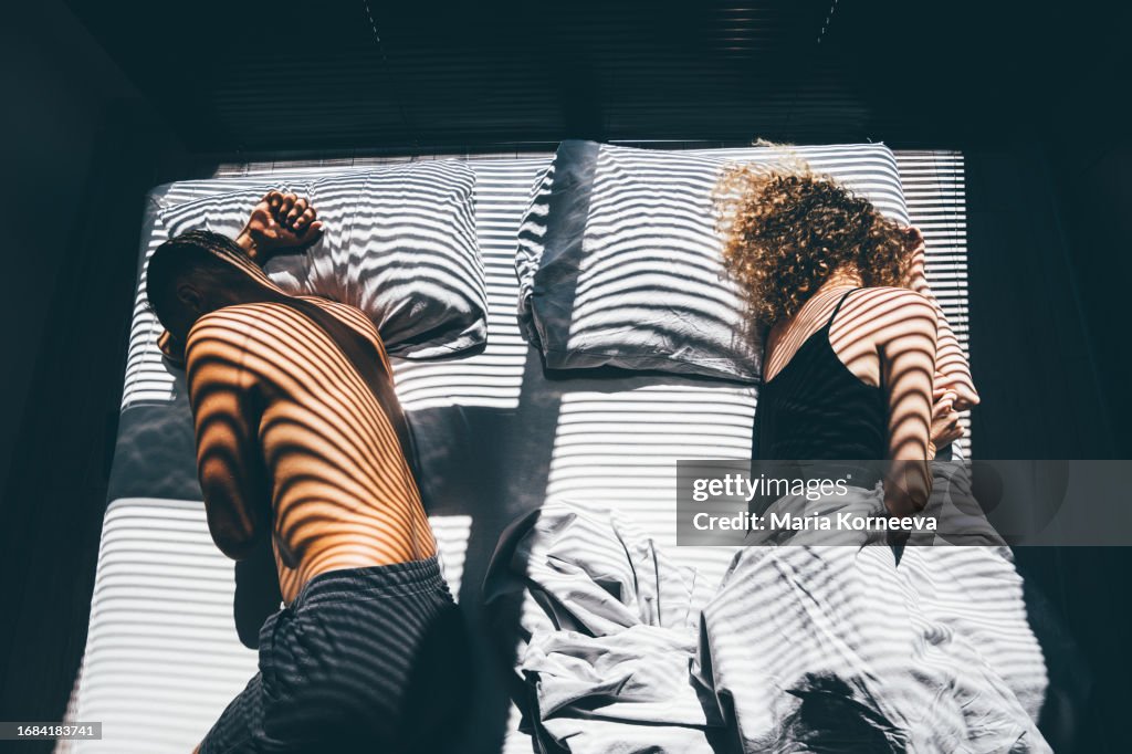 Middle-aged couple after a quarrel lies back-to-back on the bed.
