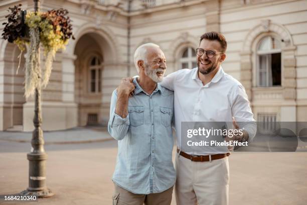 glücklicher älterer vater und erwachsener sohn gehen und reden - vatertag stock-fotos und bilder