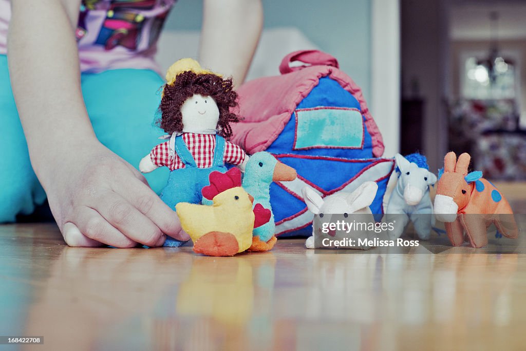 Child's hands playing with farm toys.