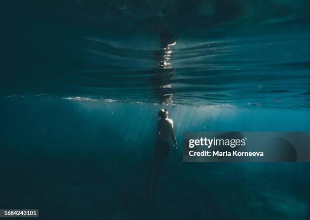 man swimming underwater in the ocean. - deep relaxation stock pictures, royalty-free photos & images