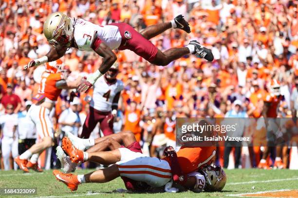 Will Shipley of the Clemson Tigers is tackled by Azareye'h Thomas of the Florida State Seminoles in the end zone as Kevin Knowles II of the Florida...