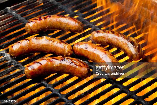 bratwurst ou cachorro-quente em uma grelha em chamas - grelha de churrasco - fotografias e filmes do acervo