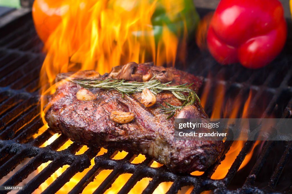 T-Bone-Steak und Paprika auf dem Grill mit Flammen