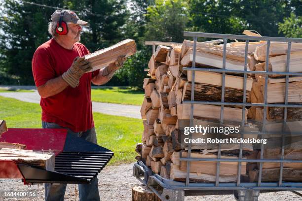 Pat Leclaire moves a piece of ash hardwood into a metal basket making firewood for his sugaring operation September 15, 2023 in Charlotte, Vermont....