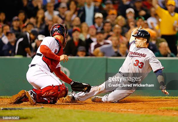 Justin Morneau of the Minnesota Twins slides safely into home plate in the sixth inning past David Ross of the Boston Red Sox during the game on May...