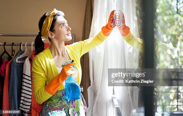woman cleaning the windows of her apartment - zuiverheid stockfoto's en -beelden