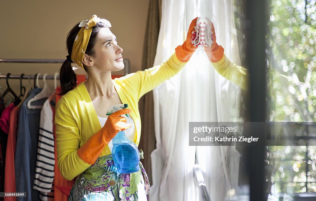 Woman cleaning the windows of her apartment
