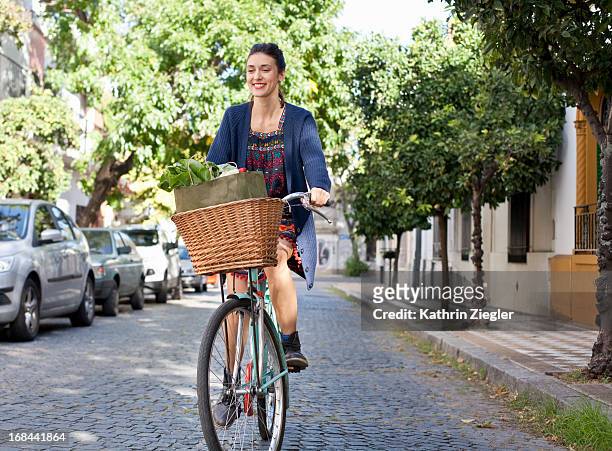 woman riding her bicycle on cobblestone street - woman bicycle stock pictures, royalty-free photos & images