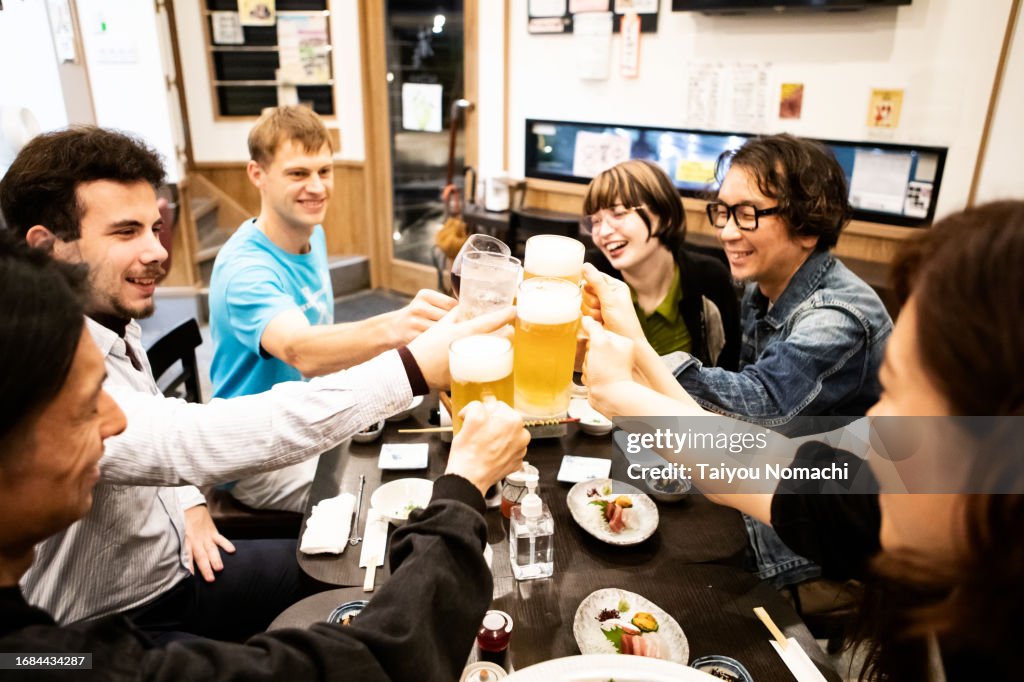 Interactions between foreign tourists and local Japanese people who came to a Tokyo izakaya.