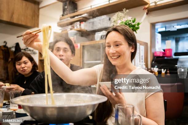 tourists from overseas try eating udon at a japanese izakaya. - japanese chopsticks stock pictures, royalty-free photos & images