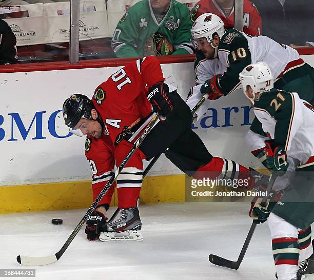 Patrick Sharp of the Chicago Blackhawks tries to control the puck under pressure from Devin Setoguchi and Kyle Bordziak of the Minnesota Wild in Game...