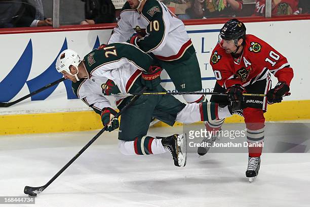 Kyle Brodziak of the Minnesota Wild slips trying to pass the puck under pressure from Patrick Sharp of the Chicago Blackhawks in Game Five of the...