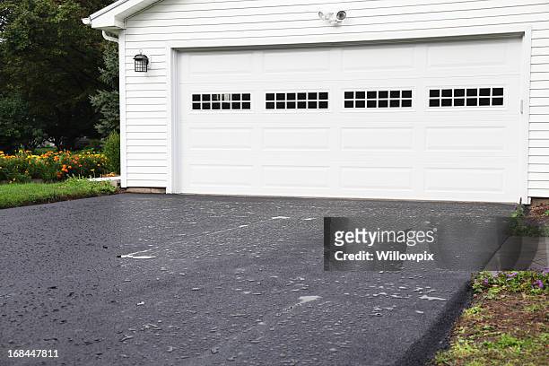 rain puddles on new asphalt driveway at residential home - carport stockfoto's en -beelden