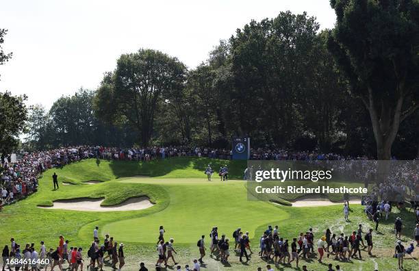 Min Woo Lee of Australia, Jon Rahm of Spain and Matt Fitzpatrick of England walk onto the second green with their caddies during Day Three of the BMW...