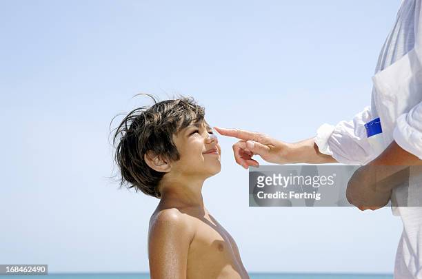 mother putting sunscreen on a child's nose - putting lotion stock pictures, royalty-free photos & images
