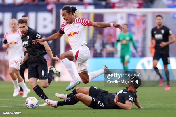 Yussuf Poulsen of RB Leipzig is challenged by Maximilian Bauer of FC Augsburg during the Bundesliga match between RB Leipzig and FC Augsburg at Red...