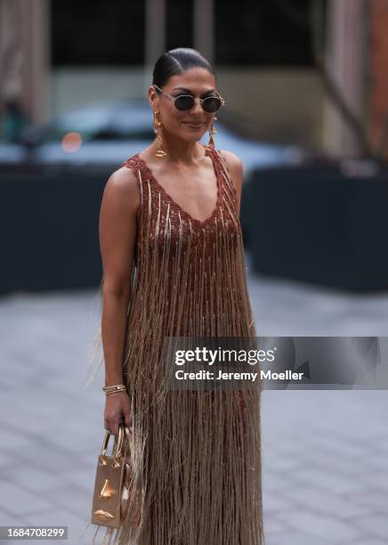 Fashion Show guest was seen wearing golden plateau high heels, Schiaparelli golden bag and golden earrings, Cartier yellow gold diamond bracelets,...