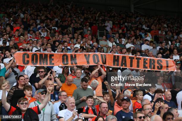 Fans of Luton Town hold a banner which reads 'Come On You Hatters!' prior to the Premier League match between Fulham FC and Luton Town at Craven...