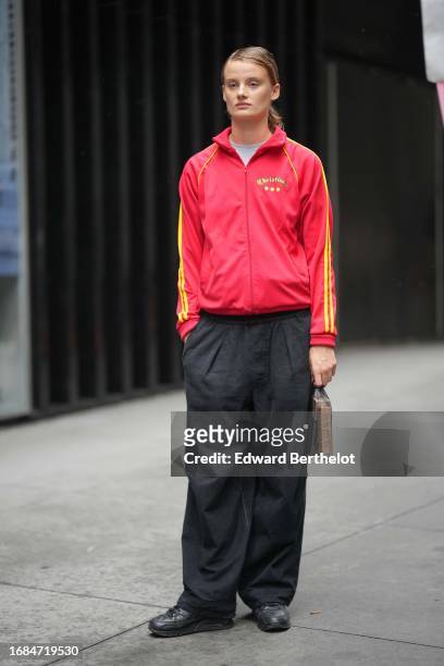 Model wears a red sportswear jacket with yellow stripes, black slack pants, sneakers , outside Jason Wu, during New York Fashion Week, on September...