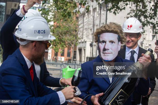 Activists stage a theatrical protest aimed at urging Keir Starmer and the Labour Party to cut ties with oil money as environmentalists march from...