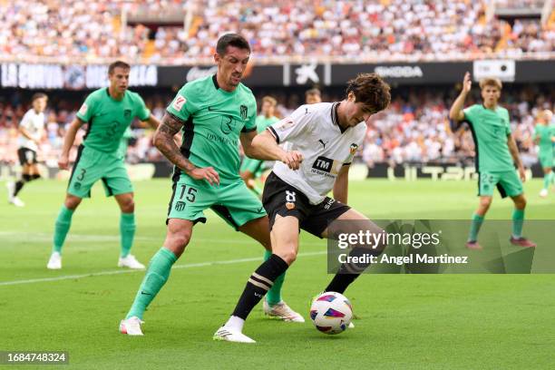 Javi Guerra of Valencia CF is challenged by Stefan Savic of Atletico de Madrid during the LaLiga EA Sports match between Valencia CF and Atletico...