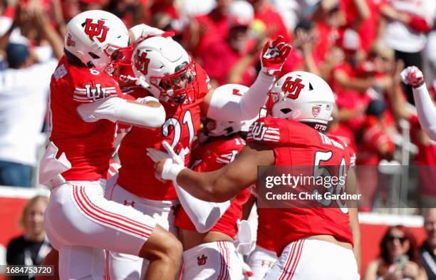 Karene Reid of the Utah Utes is congratulated by teammates Cole Bishop and Junior Tafuna after running back an interception for touchdown against the...