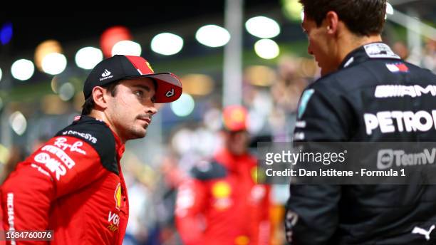 Third placed qualifier Charles Leclerc of Monaco and Ferrari talks with second placed qualifier George Russell of Great Britain and Mercedes in parc...