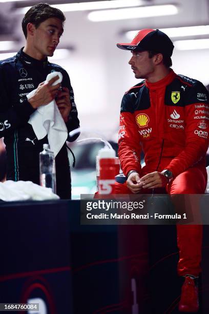 Second placed qualifier George Russell of Great Britain and Mercedes talks with third placed qualifier Charles Leclerc of Monaco and Ferrari in parc...