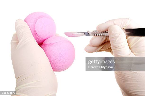 hands holding two pink tennis balls and scalpel - castration stockfoto's en -beelden