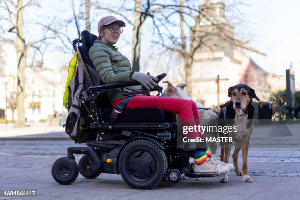 woman with disability using wheelchair exploring downtown in sweden - service animal stock pictures, royalty-free photos & images