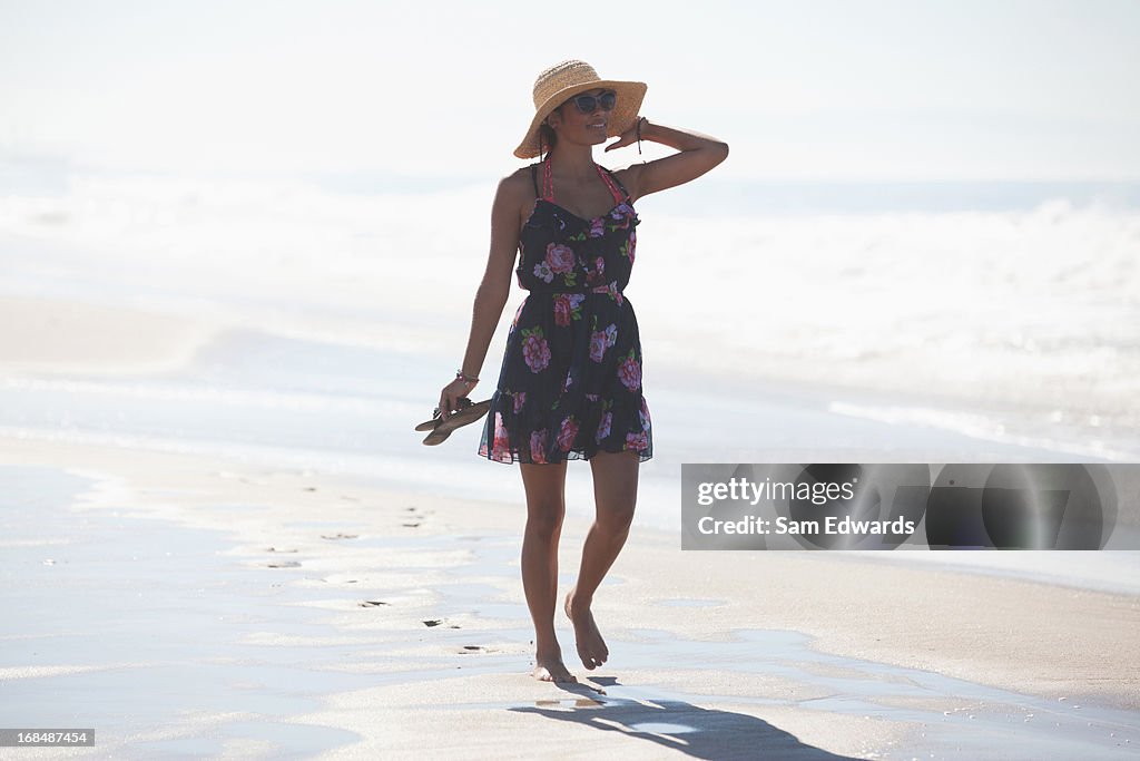 Woman carrying sandals on beach