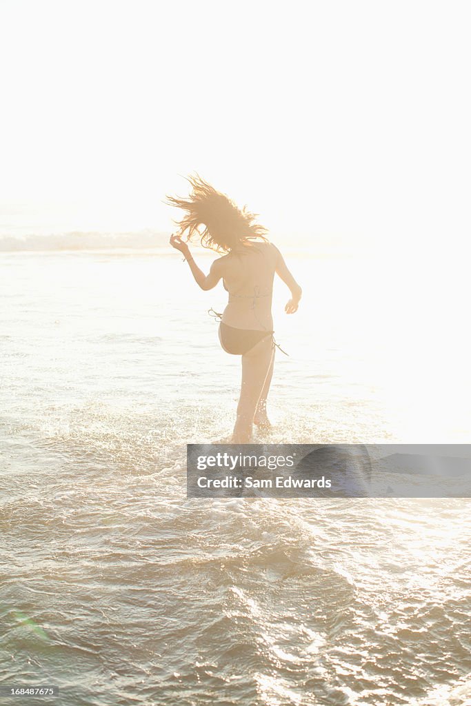 Woman walking in waves on beach