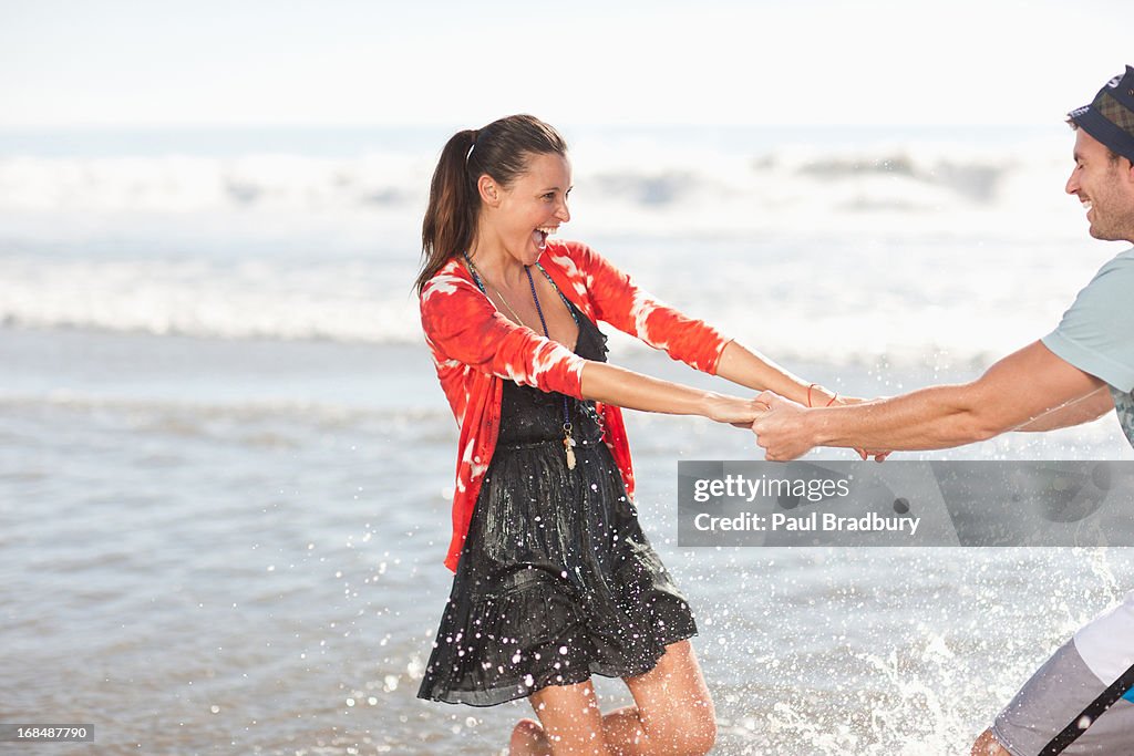 Couple playing in waves on beach