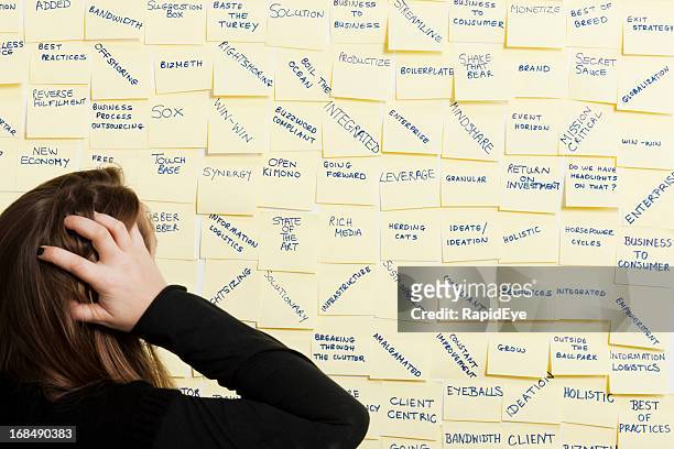worried woman looks at board full of business buzz words - technofobie stockfoto's en -beelden
